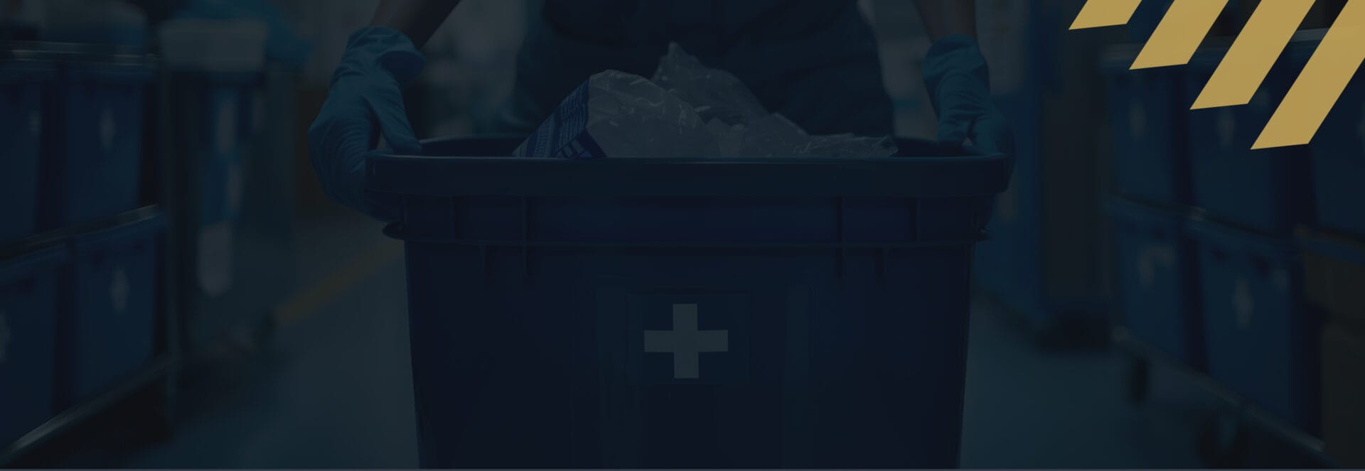 Uniformed worker in protective gloves carrying a secure document collection bin past rows of locked shredding containers