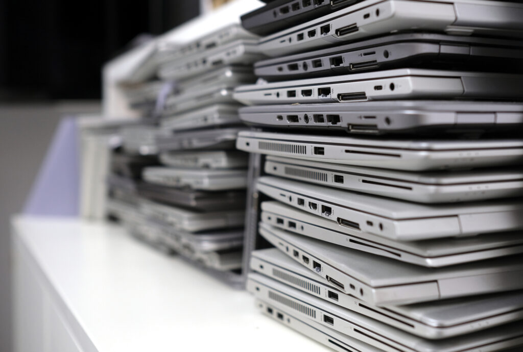 Rack of laptops in a storage room awaiting secure e-waste destruction