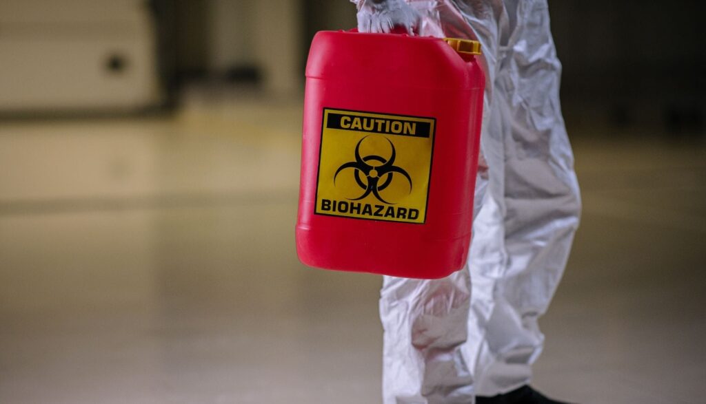 Person holding red biohazard container cautiously