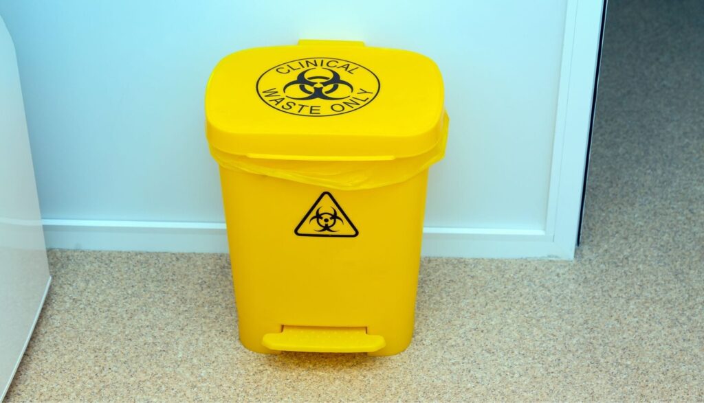 Yellow clinical waste bin with biohazard symbol.