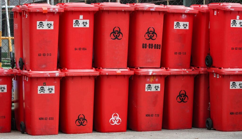 Red hazardous waste bins with biohazard symbols.
