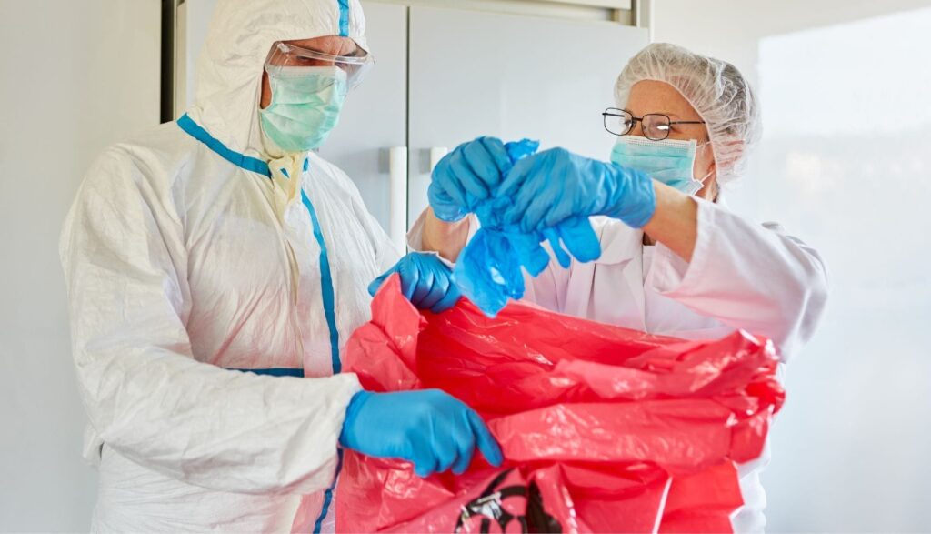 Scientists disposing biohazard waste in safety gear.