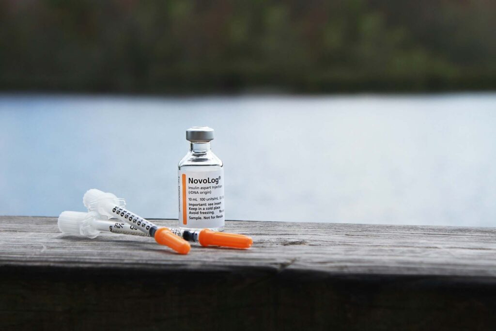 Insulin bottle and syringes by the water.