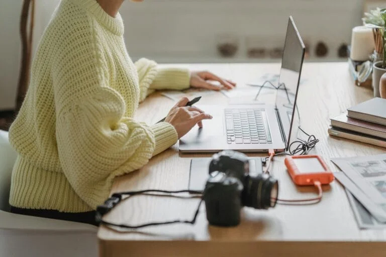 Person working on laptop with camera nearby.