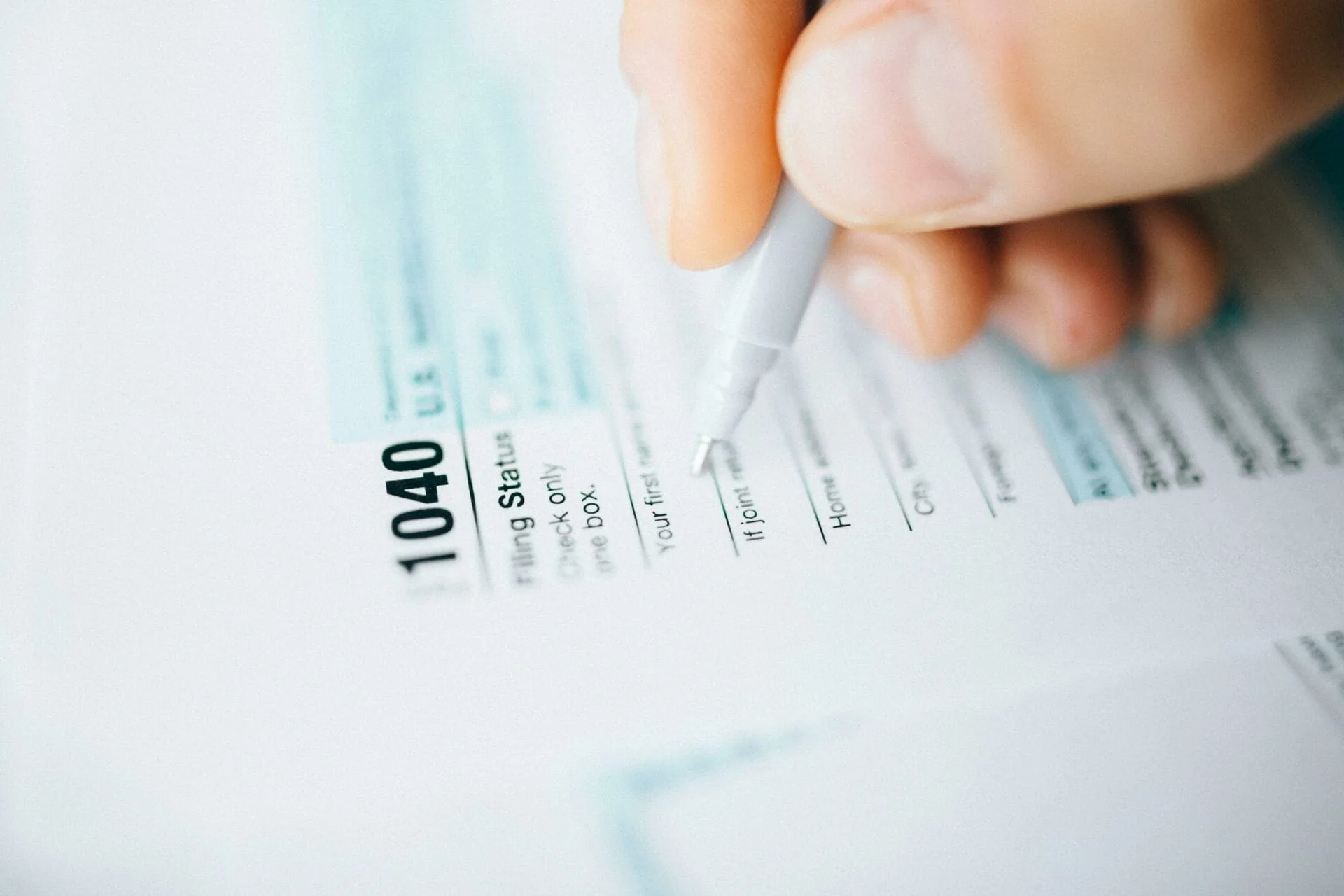 Filling out IRS Form 1040 with a pen.
