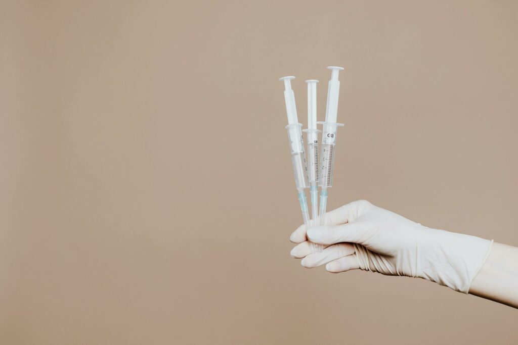 Hand holding three medical syringes.