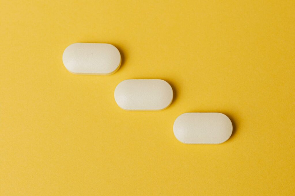 Three white pills on yellow background
